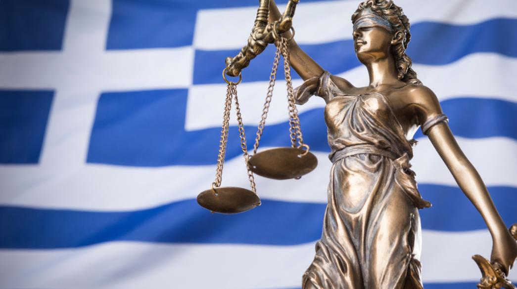 Θέμιδα μπροστά σε ελληνική σημαία